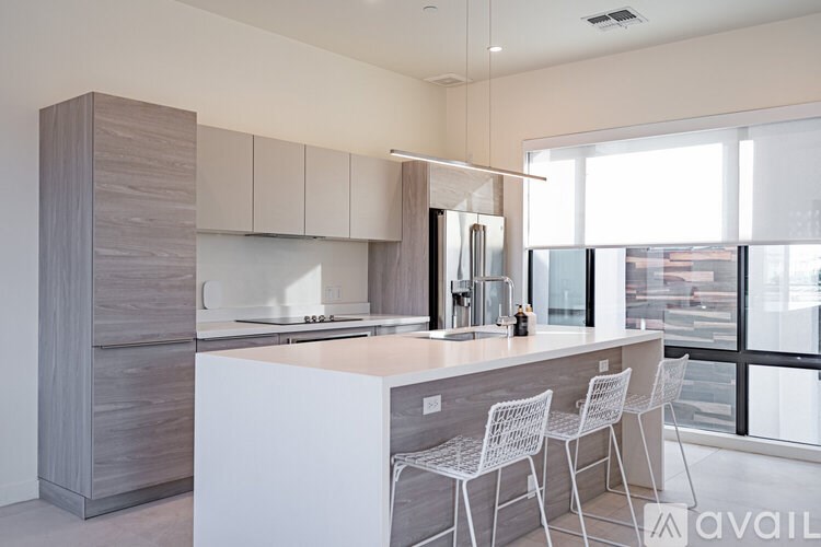 A modern kitchen with white chairs and a large island.