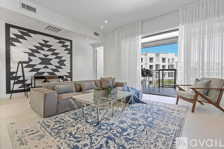 A living room with a large rug and a glass table.
