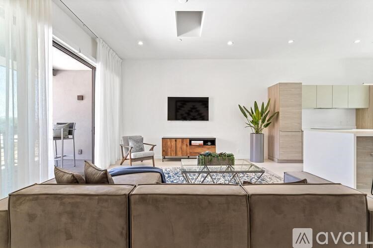 A modern living room with a brown sofa and a flat screen TV mounted on the wall.