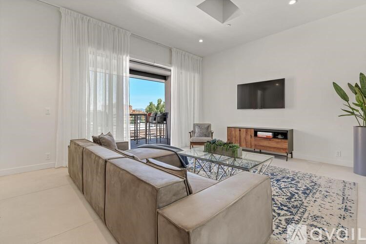 A modern living room with a large sectional sofa and a flat-screen TV mounted on the wall.