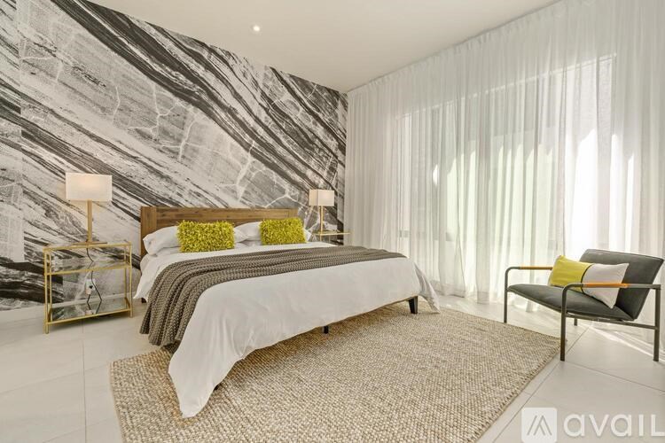 A bedroom with a marble wallpaper and a bed with a white comforter.