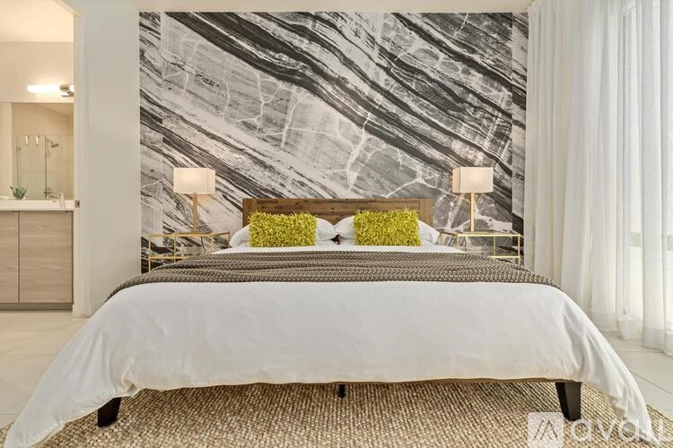 A bedroom with a large bed and a marble wallpaper.