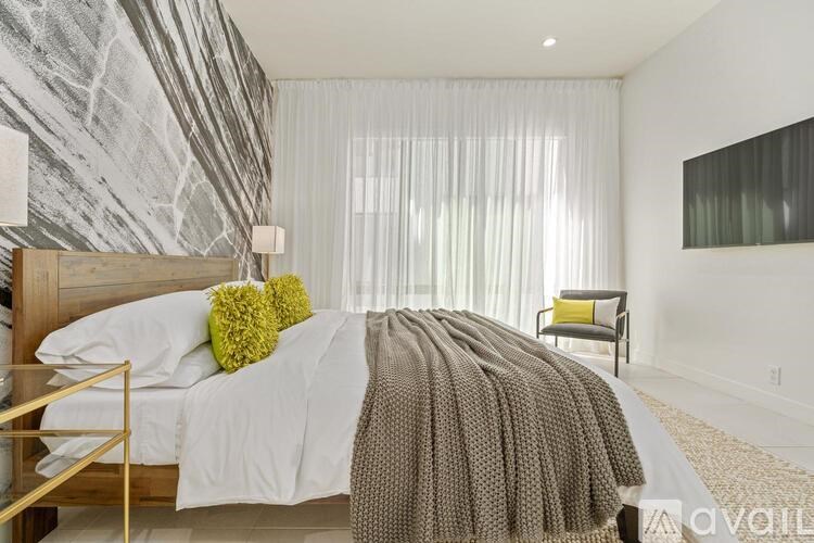 A bedroom with a bed, a chair, and a painting on the wall.