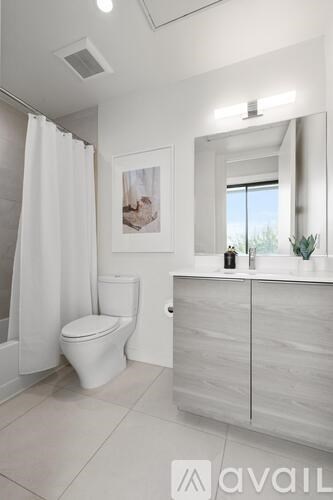 A white bathroom with a toilet, sink, and mirror.