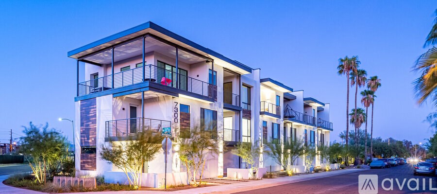 A modern multi-story building with balconies is illuminated at dusk.