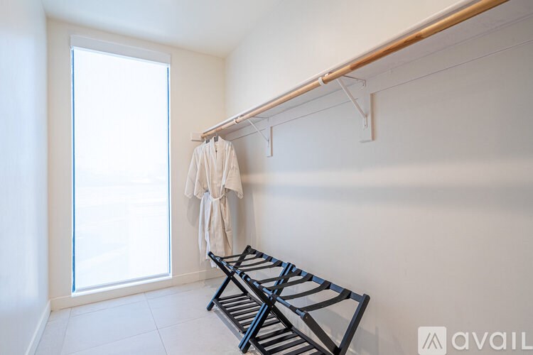 A white room with a clothes rack and a window.