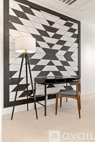 A black and white geometric patterned wall with a floor lamp and a chair in front of it.