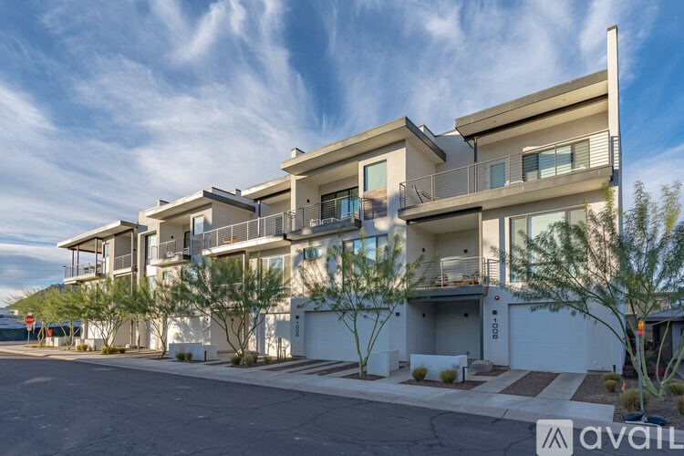 A modern two-story building with balconies and a driveway in front.