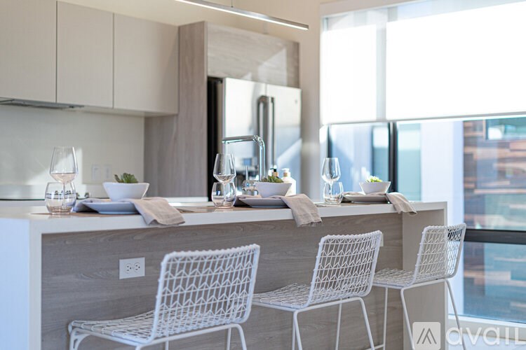 A modern kitchen with white chairs and a large window.