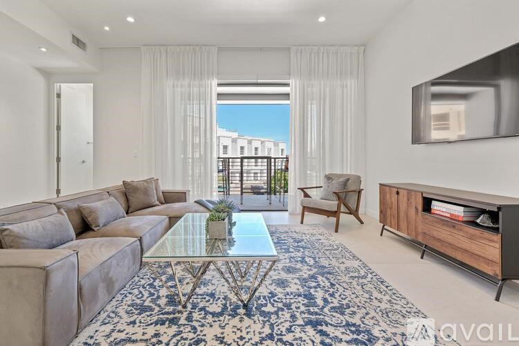 A modern living room with a glass coffee table and a large window.