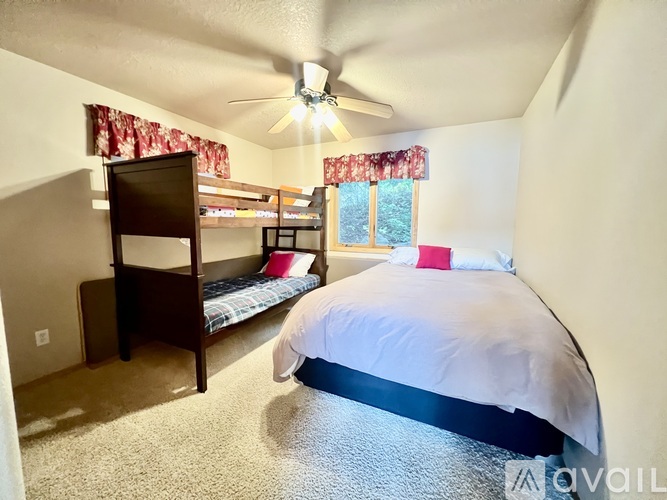 A bedroom with a bed, bunk beds, and a ceiling fan.