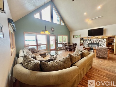 A living room with a large couch and a stone fireplace.