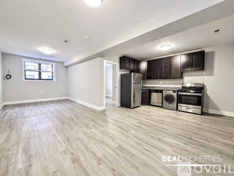 A spacious kitchen with wooden flooring and stainless steel appliances.