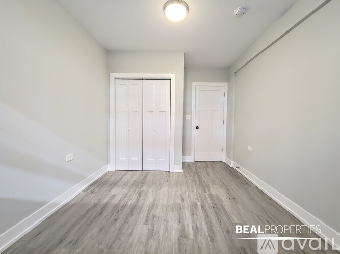 A spacious room with wooden flooring and two white doors.