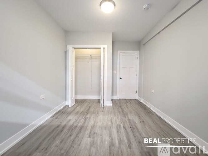 A spacious room with wooden flooring and white walls.
