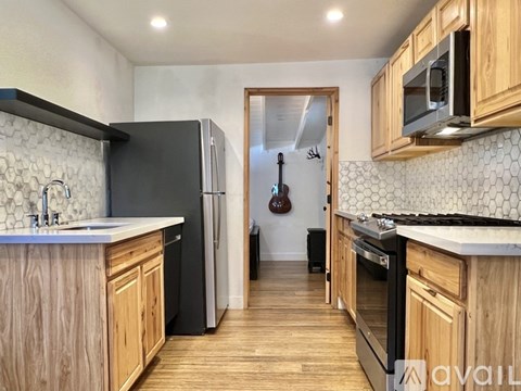 A kitchen with wooden cabinets and a black fridge.