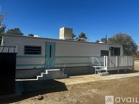 A silver trailer with a green door and a white porch.