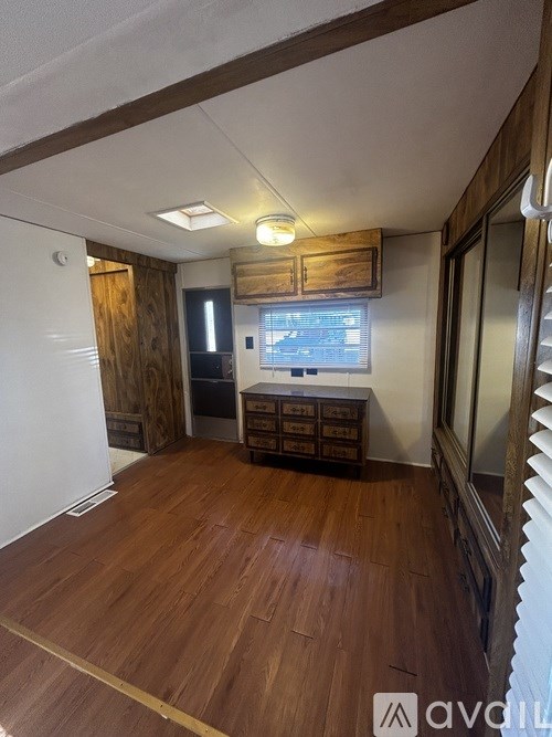 A room with wooden floors and a window with blinds.