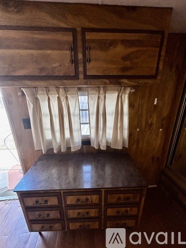 A wooden desk with drawers and a cabinet above it.