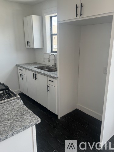 A kitchen with white cabinets and a granite countertop.