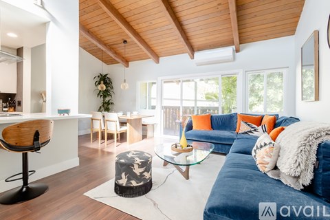 A living room with a blue couch and a wooden ceiling.
