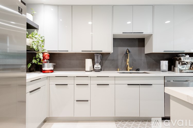A modern kitchen with white cabinets and a stainless steel refrigerator.