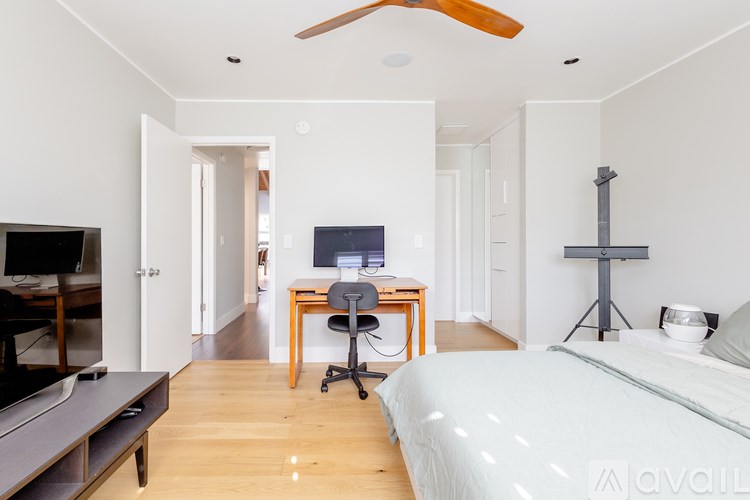 A bedroom with a bed, desk, and television.