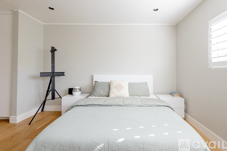 A bedroom with a bed, a tripod, and a window.