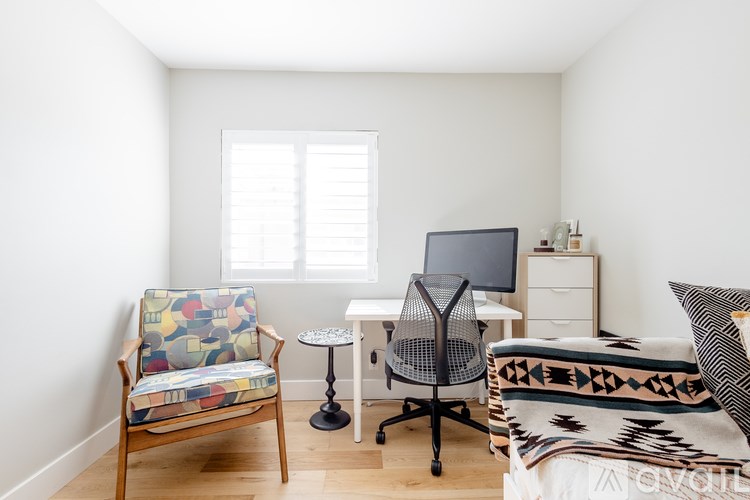 A room with a chair, a desk, and a bed.