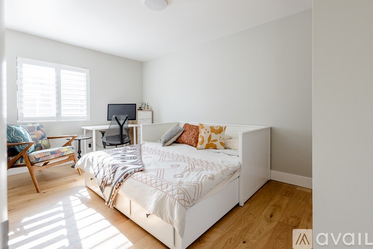 A bedroom with a bed, a chair, and a desk with a computer.