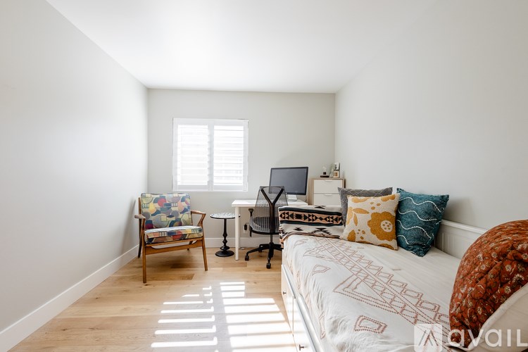 A bedroom with a bed, chair, and desk.