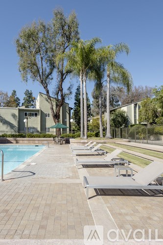 A pool area with sun loungers and a building in the background.