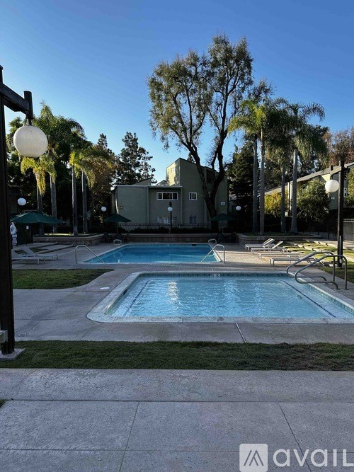 A pool surrounded by trees and a building in the background.