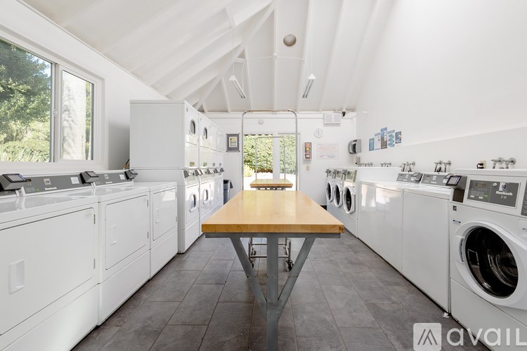 A laundry room with a table in the middle of washing machines.