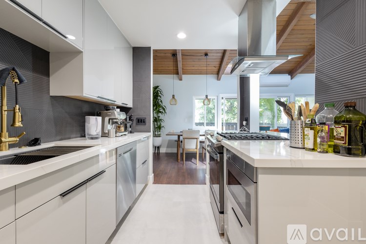 A modern kitchen with white cabinets and a wooden ceiling.