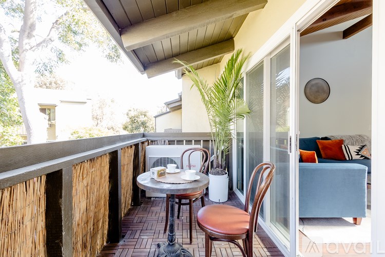 A balcony with a table and chairs overlooking a living room.