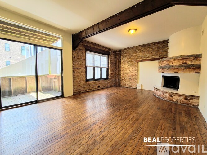 A spacious room with wooden floors and a fireplace.