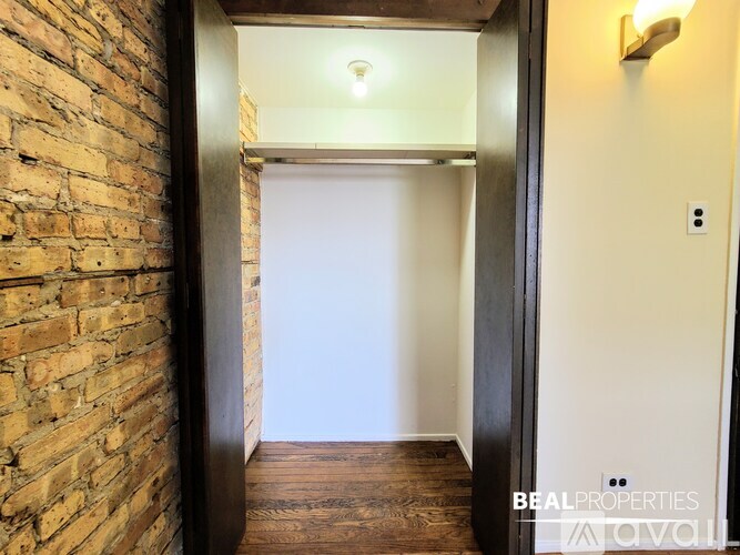 A hallway with a brick wall on the left and a wooden floor.