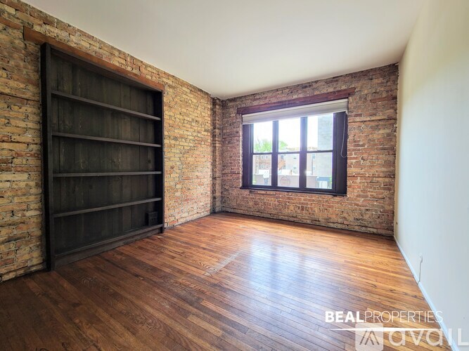 A room with a brick wall and wooden flooring is available for rent.