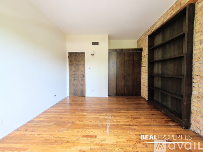 A room with wooden floors and a brick wall with a shelf.