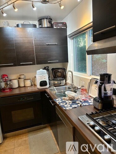 A kitchen with a white refrigerator, brown cabinets, and a black mat on the floor.