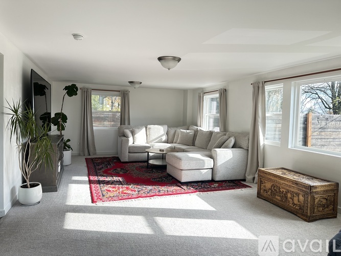 A living room with a white sofa set and a red rug.
