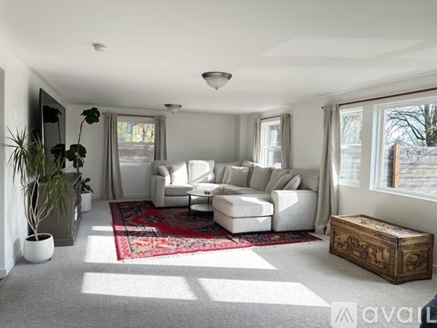 A living room with a white sofa set and a red rug.