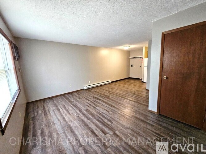 A room with wooden flooring and a door on the right side.