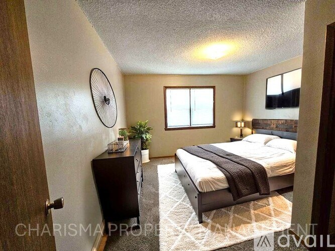 A bedroom with a bed, dresser, and window.