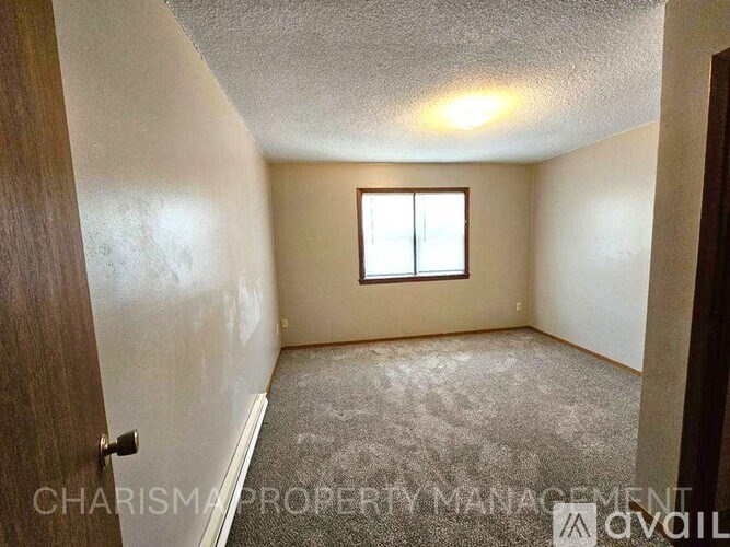 A room with a window and carpeted floor.