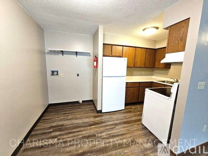 A small kitchen with a white fridge and wooden cabinets.