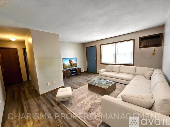 A living room with a white couch, a coffee table, and a flat screen TV.