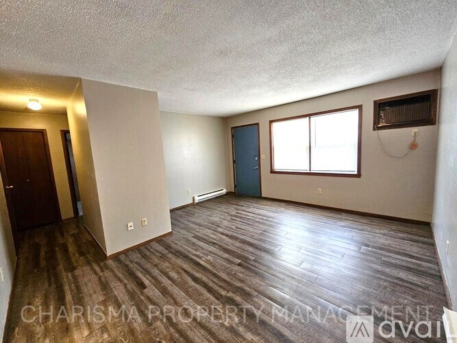 A room with wooden flooring and a window with blinds.