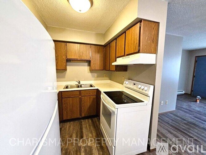 A kitchen with white appliances and wooden cabinets.